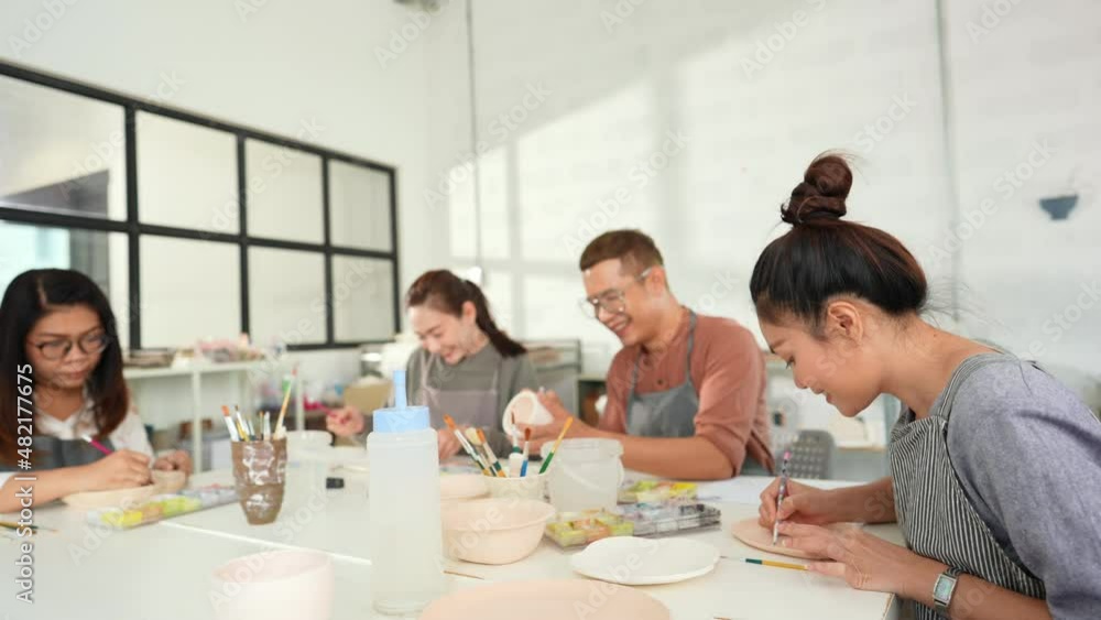 Group of Happy Asian man and woman friends enjoy and having fun indoor lifestyle painting self-made pottery together at pottery studio. Hobby leisure activity handmade ceramic art painting workshop. Group of Happy Asian man and woman friends enjoy and having fun indoor lifestyle painting self-made pottery together at pottery studio. Hobby leisure activity handmade ceramic art painting workshop.