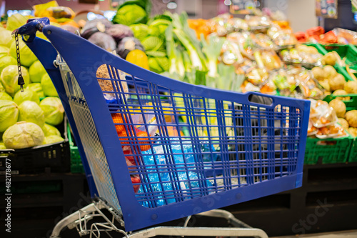 A shopping cart with grocery products in a supermarket photo