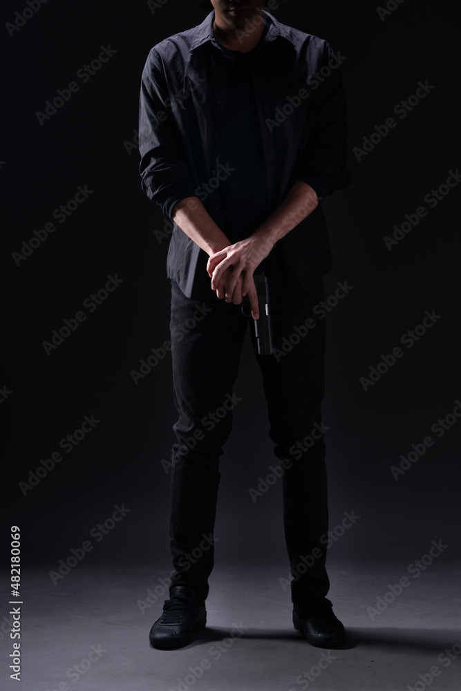 man with a gun, Man in black holding a gun standing in the dark on a black background. man with a gun, Man in black holding a gun standing in the dark on a black background.