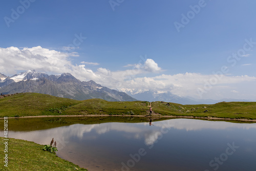 A woman at the Koruldi Lake with an amazing view on mountain ridges near Mestia in the Greater Caucasus Mountain Range, Upper Svaneti, Country of Georgia. Reflection in the water. Wanderlust. Trekking