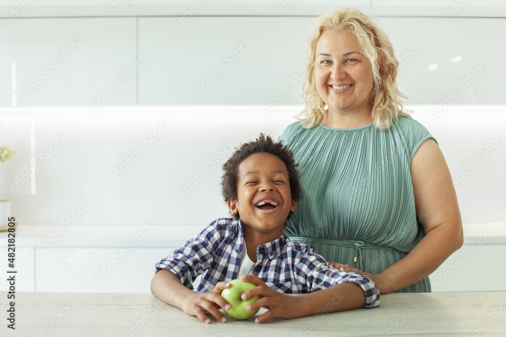 Fototapeta premium Happy mother and child boy laughing and holding green apple fruit. Happy family.