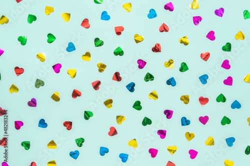 Hearts in red, yellow, beach, green and purple are better on a turquoise blue and green background. Minimal concept of Valentine's Day. Scattered love.