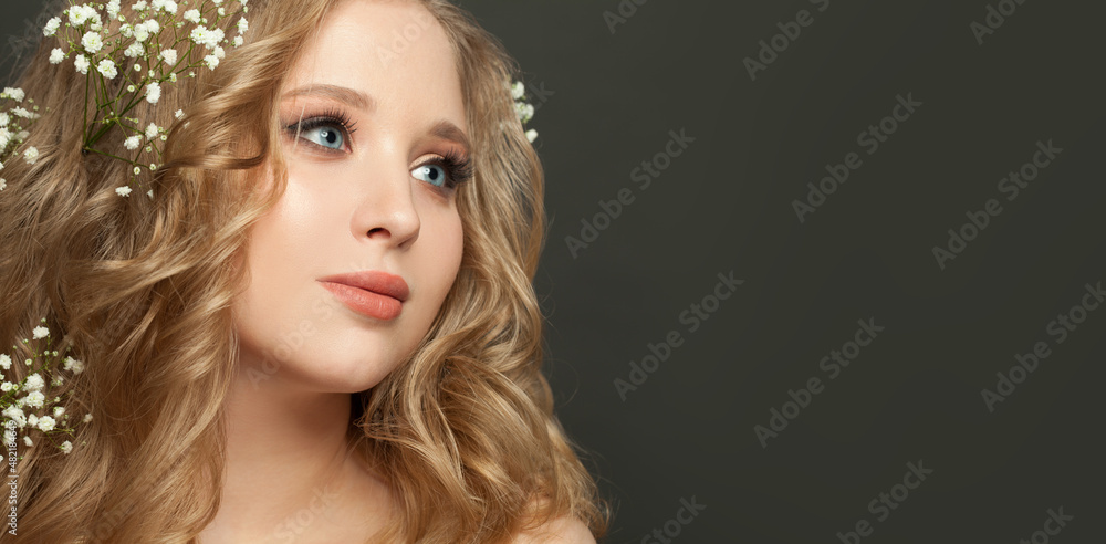 Young smiling woman with blonde hair and white flowers on black background