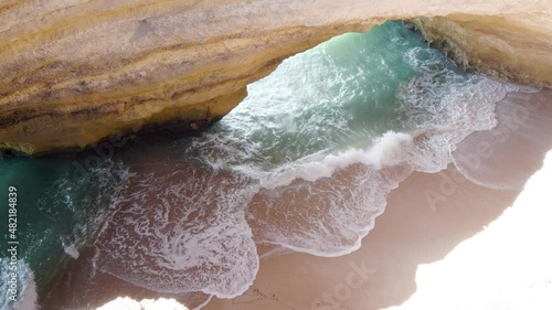 Overhead view of waves breaking on sandy beach inside benagil cave