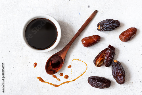 Natural date syrup in a bowl with whole dates in the background