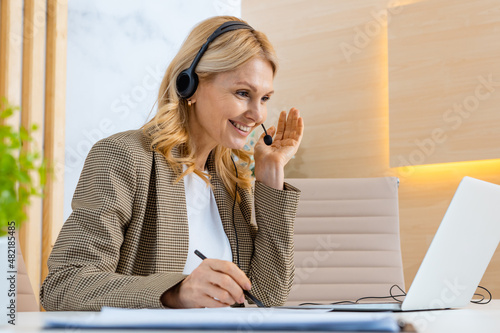 Businesswoman sitting at computer desk in the office with microphone headset photo