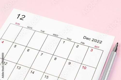 December 2022 calendar sheet with pen on pink background.