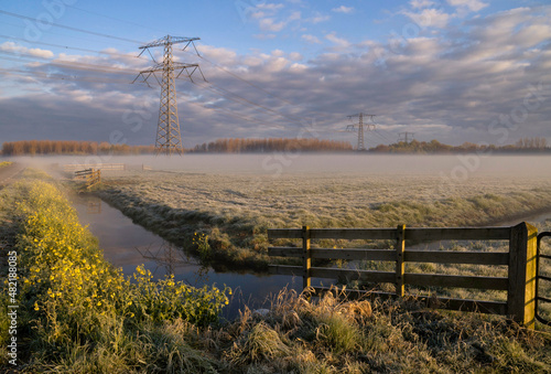 Morning fog above a meadow with electricity pylons