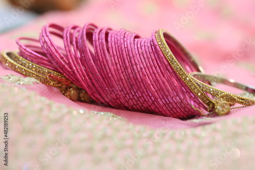 dozens of pink glass decorative bangles spread on pink lehenga photo