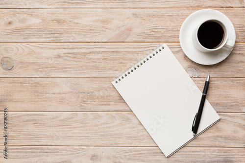 Modern office desk table with notebook and other supplies with cup of coffee. Blank notebook page for you design. Top view  flat lay