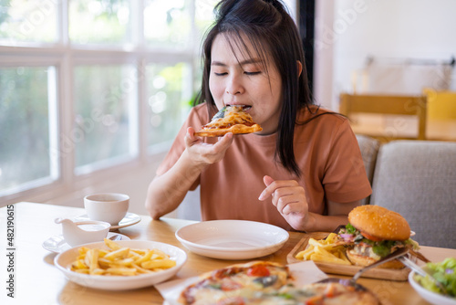 Cheerful girl with pizza in their hands. Young woman eating pizza with feeling enjoy and happy enjoy in the restaurant in leisure time. dine in the restaurant. Italian food.