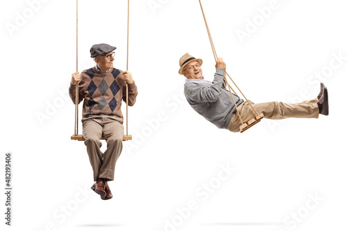 Elderly man sitting on a wooden swing and looking at another man swinging