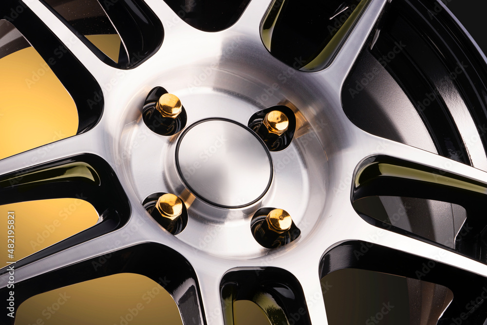 bright yellow alloy wheel and wheel nuts on a gradient black and yellow background, close-up details. auto tuning and auto parts bright yellow alloy wheel and wheel nuts on a gradient black and yellow background, close-up details. auto tuning and auto parts