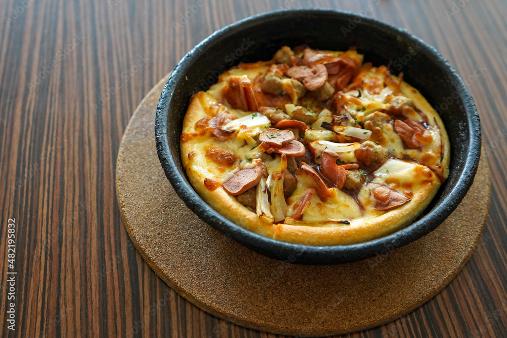 Barbeque beef pizza hut served on a black plate or bowl with a brown textured wooden table background. Barbeque beef pizza hut served on a black plate or bowl with a brown textured wooden table background.