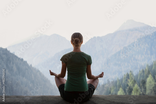 Young woman practicing yoga in mountains at sunset. Harmony, meditation, healthy lifestyle, relaxation, yoga, self care, mindfulness concept photo