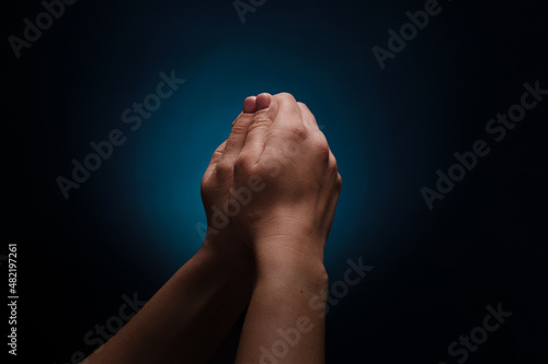 Praying hands with faith in religion and belief in God over dark background