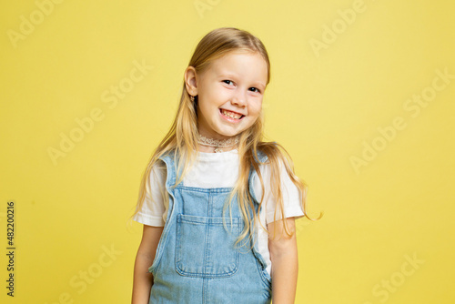 Smiling baby girl with blonde hair isolated on yellow