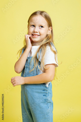 Baby girl with blonde hair isolated on yellow smiling