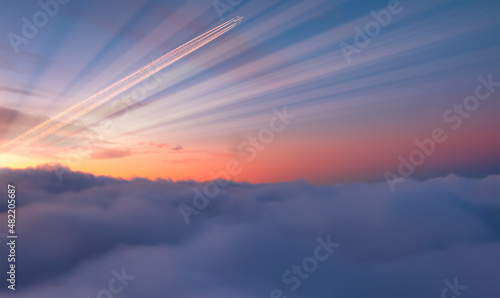 Fotografia Jet airplane with trail of fuel on blue sky at sunset