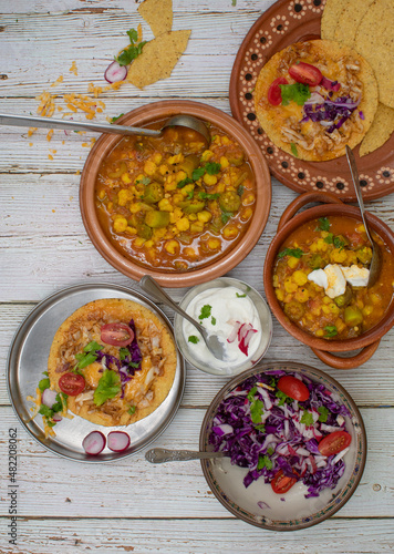 Vegetarian okra pozole and corn quesadillas in traditional Mexican clay dishes, wooden table.