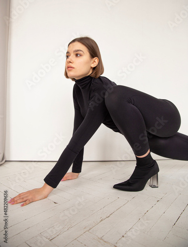 Crawling like a cat woman with square hair and white skin totally in black on grey