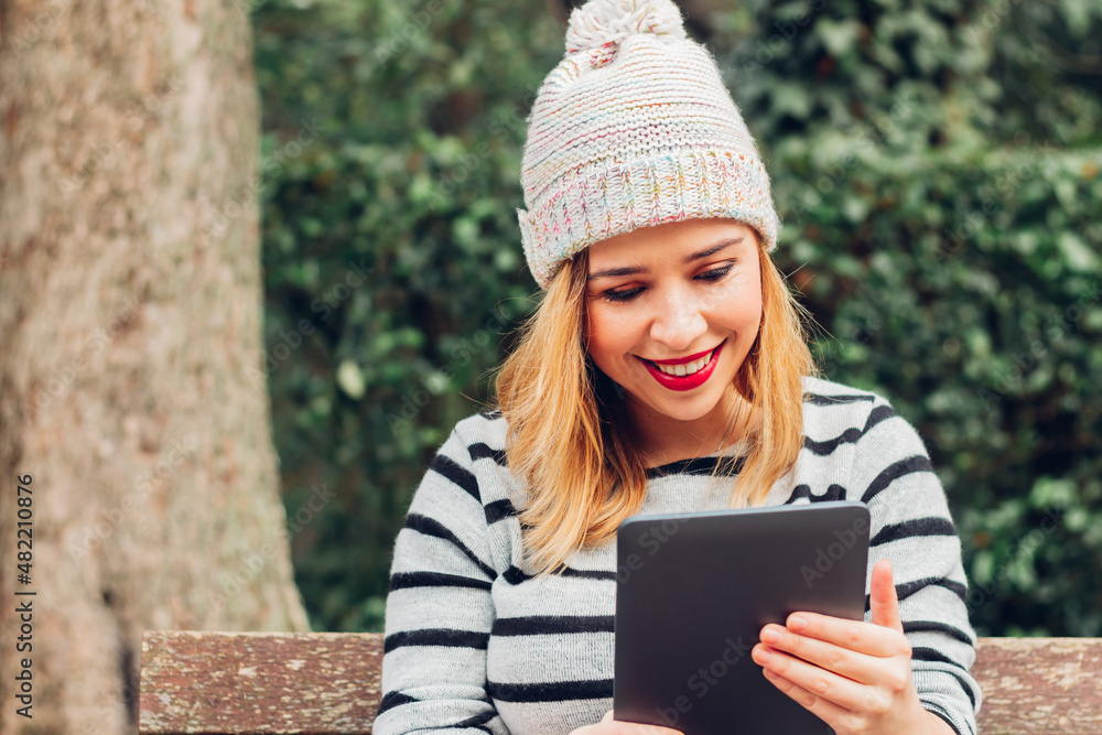 Smiling young woman using her digital tablet with a happy and amused face. Smiling young woman using her digital tablet with a happy and amused face.