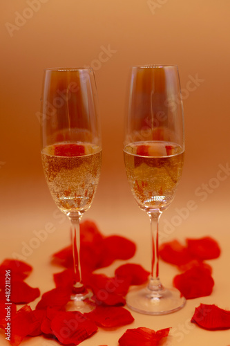 due flûte di spumante su un tavolo pieno di petali di rosa 
