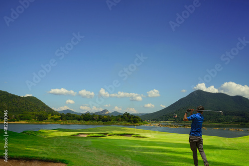 Golfer posing stand near golf bag with beautiful sun sky background.