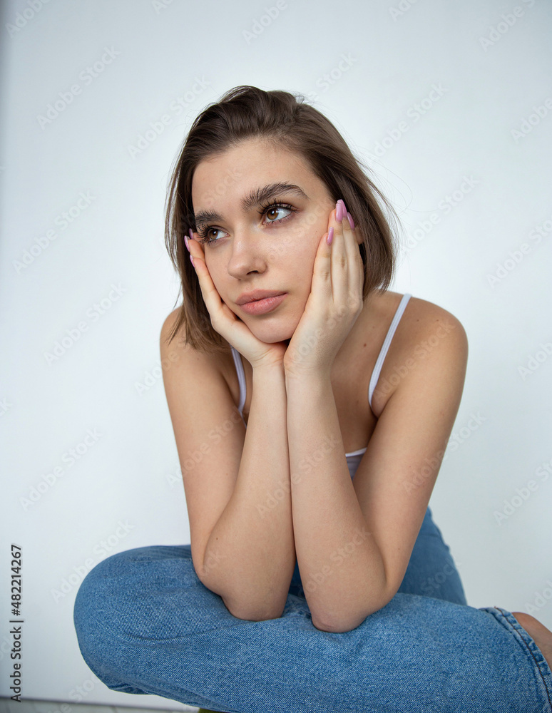 White european woman with bob cut on white holding her head in hands White european woman with bob cut on white holding her head in hands