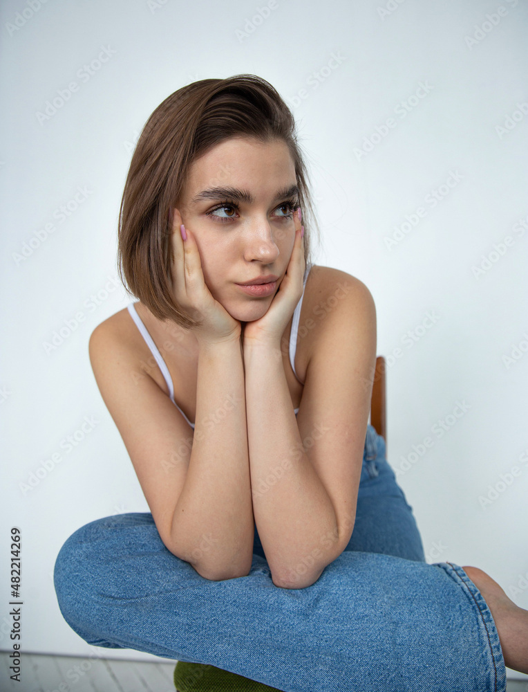 White european woman with bob cut on white holding her head in hands White european woman with bob cut on white holding her head in hands