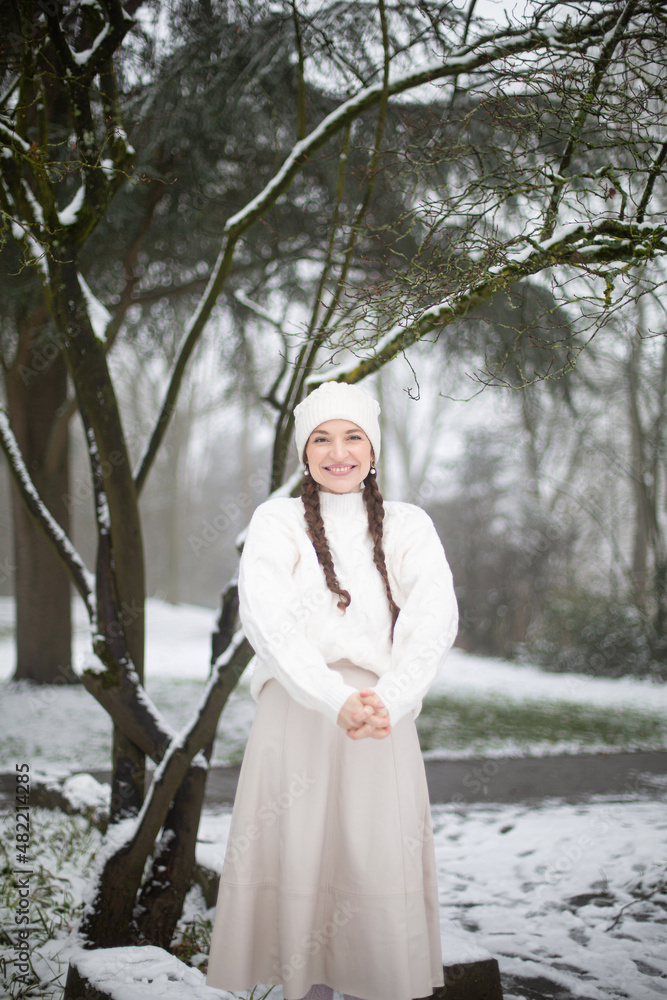 Smiling young woman with white skin and long pigtails in winter park with snow Smiling young woman with white skin and long pigtails in winter park with snow