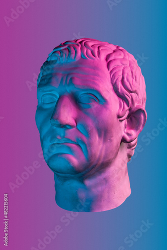 Blue purple gypsum copy of ancient statue of Guy Julius Caesar Octavian Augustus head for artists isolated on color background. Renaissance epoch. Plaster sculpture of man face.Template for art design