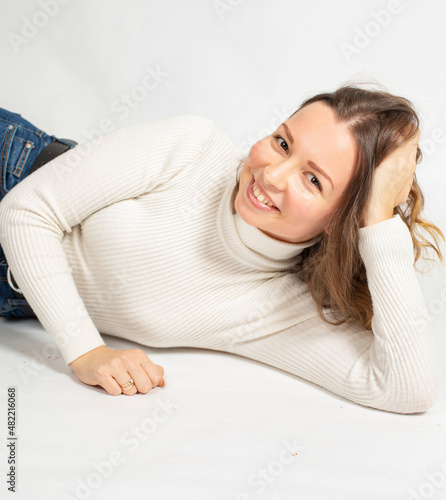 Attractive young european woman in warm white jumper isolated on white leaning in hand