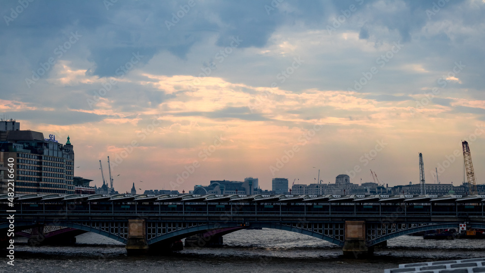 Blackfriars bridge on an overcast day, with sunlight in the far distance