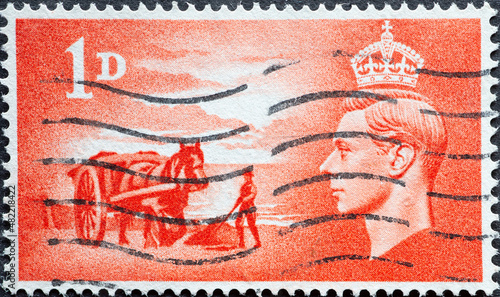 United Kingdom - circa 1948: a postage stamp from United Kingdom , showing a portrait of King George VI . Farmer with horse plowing his field. 1d - Gathering Vraic (seaweed)