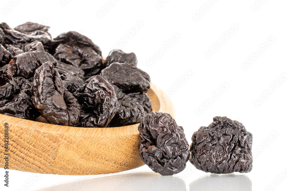 Several organic sweet prunes on a wooden tray, close-up, isolated on white. Several organic sweet prunes on a wooden tray, close-up, isolated on white.