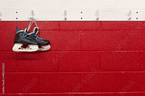 Photography Hockey skates hanging over red wall in locker room with copy space