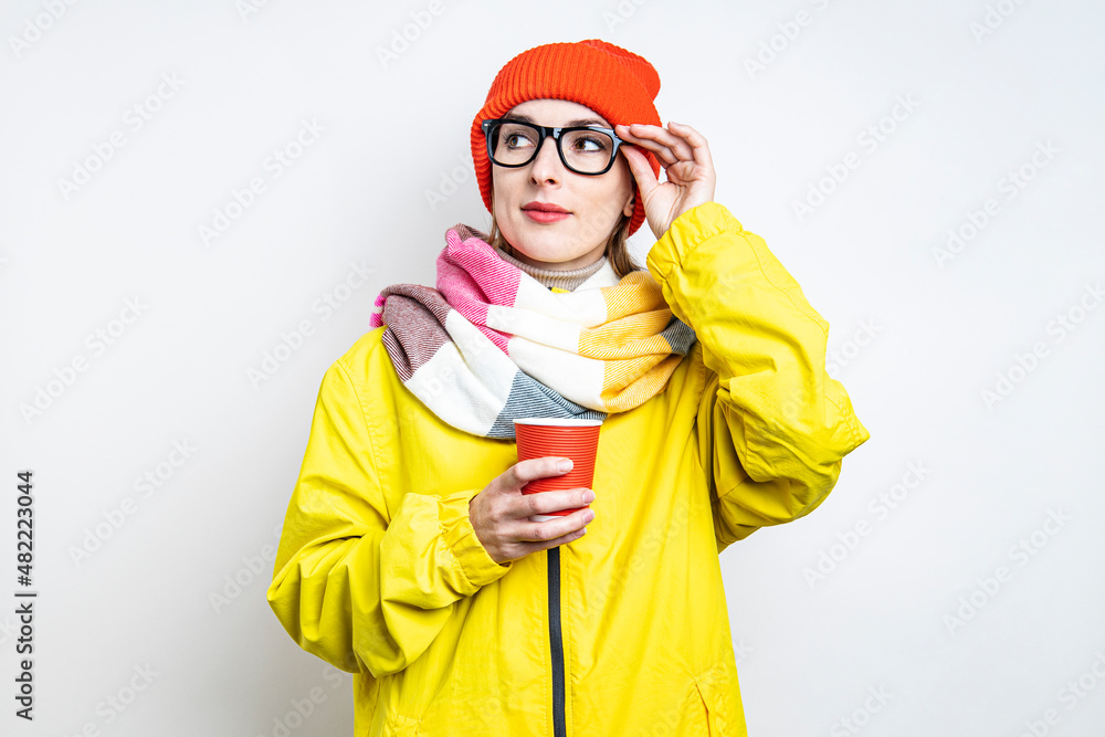 Young woman in glasses with a paper cup on a light background. Young woman in glasses with a paper cup on a light background.