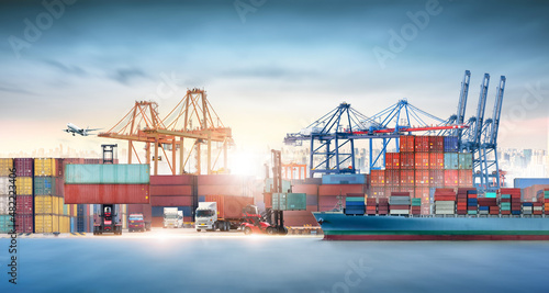 Global business logistics import export and container cargo freight ship during loading at industrial port by crane, container handlers, cargo plane, truck on highway, transportation industry concept