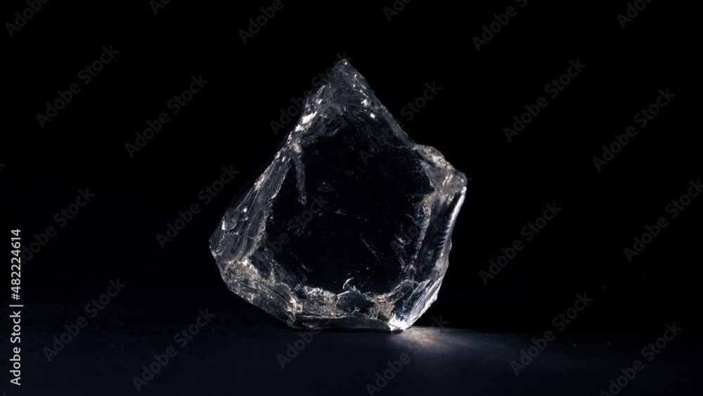 Rough diamond. Transparent stone. A piece of ice. Black background. Rough diamond. Transparent stone. A piece of ice. Black background.