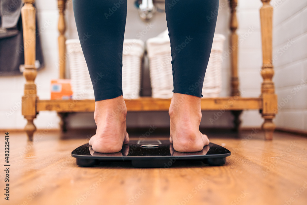 Close up of Woman on a a bathroom scale. Diet problems concept Close up of Woman on a a bathroom scale. Diet problems concept