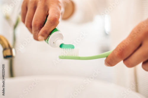 Close up of woman putting toothpaste on toothbrush