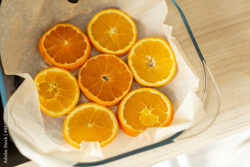 orange circles are laid out on parchment in a transparent baking dish orange circles are laid out on parchment in a transparent baking dish
