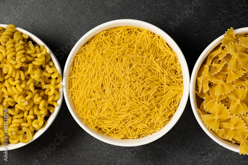 Close up of several types of dry pasta in a plate on dark background photo