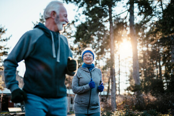 An older married couple enjoys exercising and jogging on a beautiful sunny winter day.