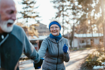 An older married couple enjoys exercising and jogging on a beautiful sunny winter day.
