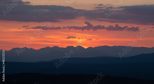 Silhouettes of mointains against the warm sunset that lights up the clouds