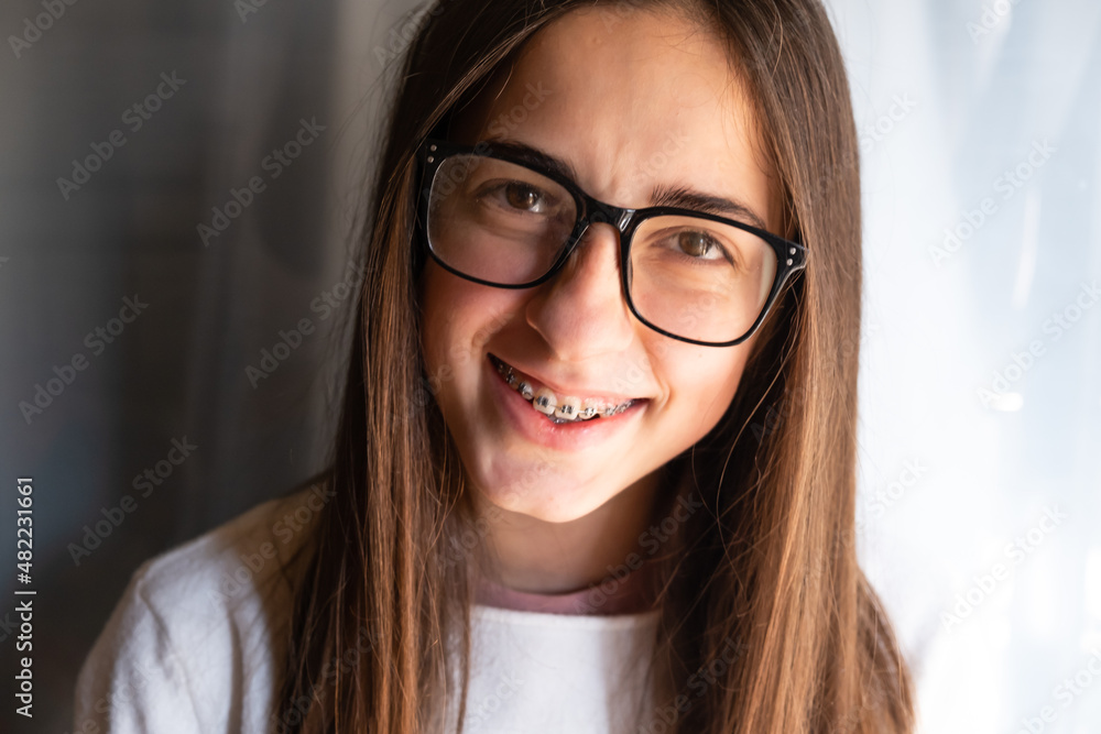 Happy smiling girl with dental braces and glasses. Funny expression. Adolescence. Happy smiling girl with dental braces and glasses. Funny expression. Adolescence.