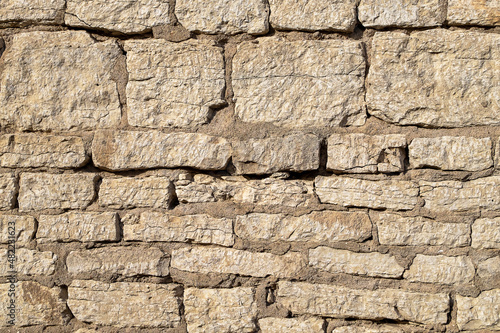 Fragment of ancient medieval fortress wall made of limestone. Vintage background. Natural old stone. Pattern in medieval style. Elements of medieval architecture. Selective focus.