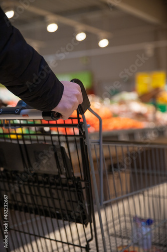 Billede på lærred jeune homme qui fait ses courses dans un supermarché, il pousse son caddie au milieu des rayons
